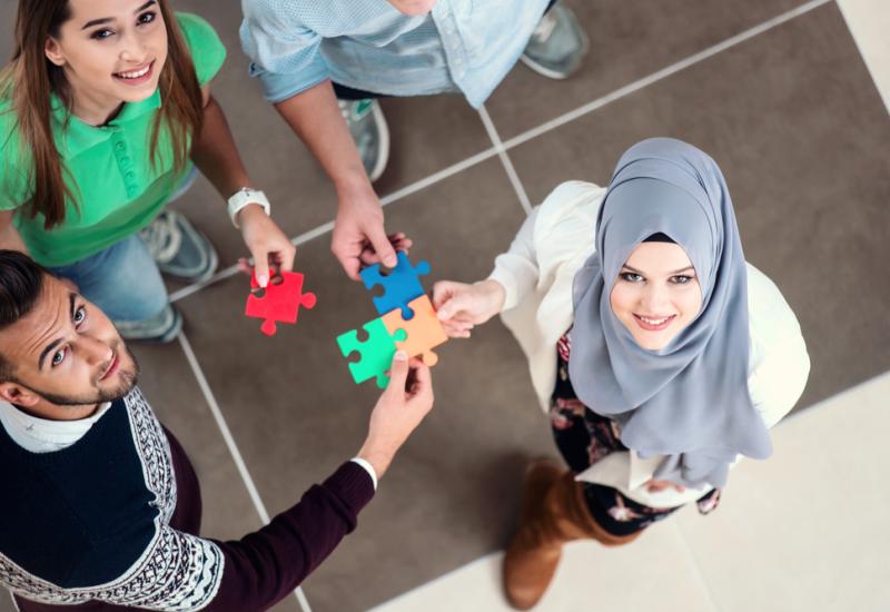 A group of people linking together jigsaw pieces representing integration